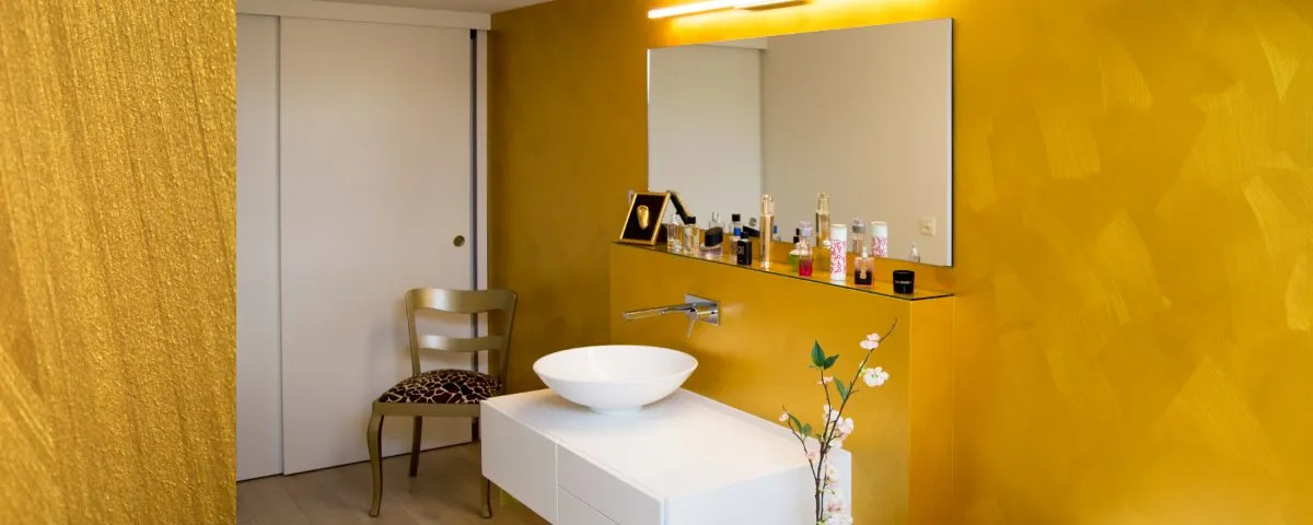 Badezimmer mit goldfarbener dekorativer Wandbeschichtung